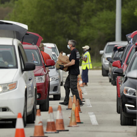 Workers and volunteers help load cars with food at a San Antonio Food Bank drive-through distribution in San Antonio, Tuesday, April 7, 2020. The new coronavirus causes mild or moderate symptoms for most people, but for some, especially older adults and people with existing health problems, it can cause more severe illness or death. (AP Photo/Eric Gay)