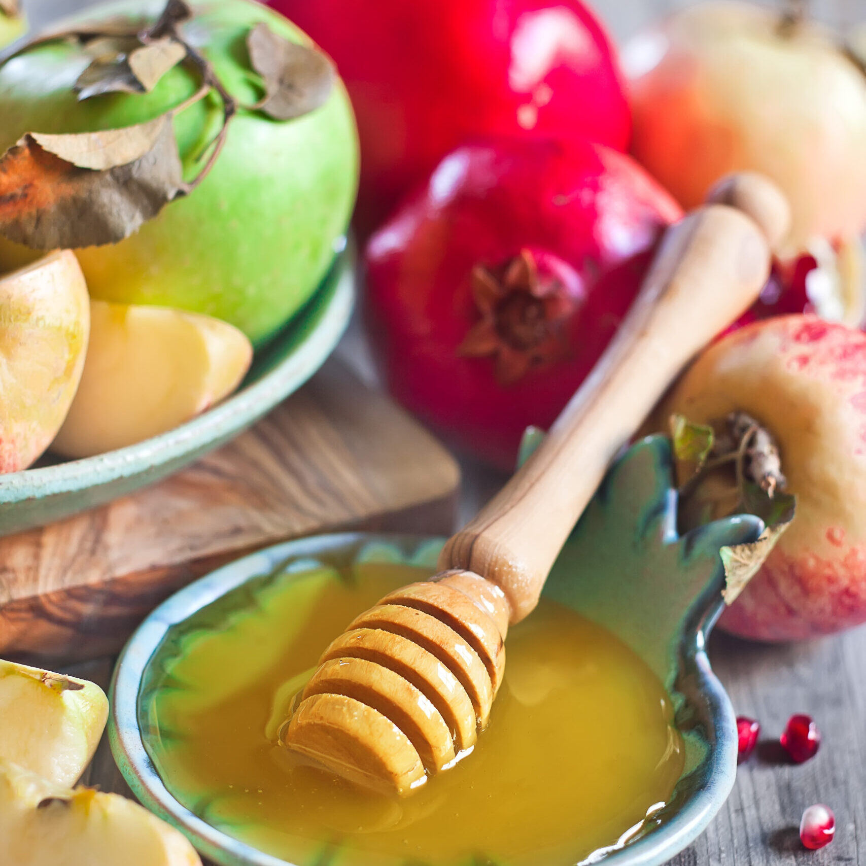 Pomegranate, apple and honey, traditional food of jewish New Year celebration, Rosh Hashana. Selective focus.