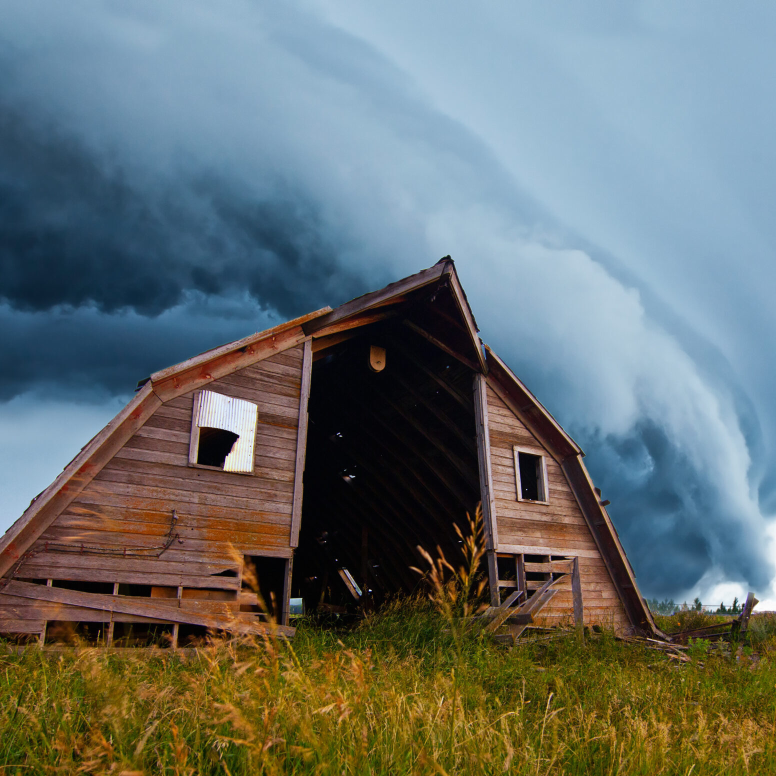 tornado forming behind old barn on american plains